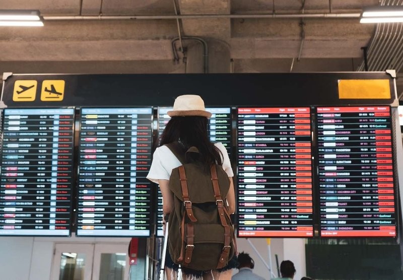 Eine Frau schaut auf eine Anzeigetafel am Flughafen.