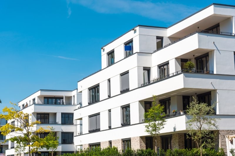Modern, white multi-storey residential complex with balconies.